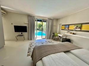 1 Schlafzimmer mit einem Bett, einem TV und einem Pool in der Unterkunft Pure Guest House in Hout Bay