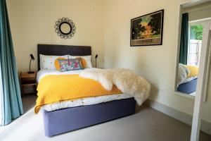 a bedroom with a bed with a yellow blanket and a mirror at Oak Cottage at Gravel Farm in Stretham
