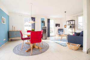 a living room with a table and red chairs at Ferienhaus Muscheltaucher in Kramerhof