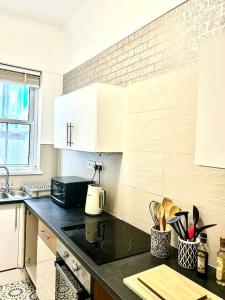 een keuken met witte kasten en een zwart aanrechtblad bij Saxon Cottage St Leonards on sea in Hastings