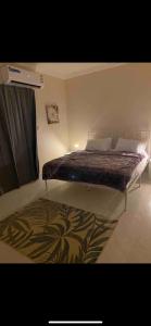 een slaapkamer met een bed met een deken en een tapijt bij البندرية in Al Khobar