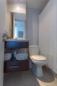 a bathroom with a toilet and a sink and a mirror at Kennedy Apartments Los Militares in Santiago