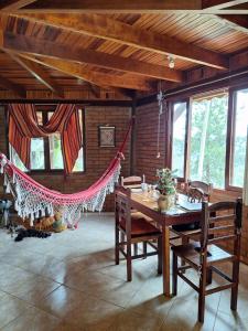Habitación con mesa, sillas y hamaca. en Casa das nuvens en Itatiaia