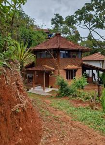 una casa con techo de paja en un camino de tierra en Casa das nuvens en Itatiaia