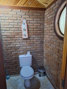 a bathroom with a toilet in a brick wall at Casa das nuvens in Itatiaia