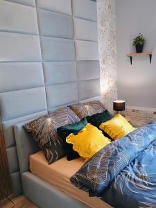a bed with four pillows on top of it at Apartament EM in Krosno
