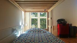 Un dormitorio con una cama y una ventana con una maleta en O2 Hostel, en Oporto