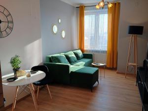 a living room with a green couch and a table at Apartament EM in Krosno