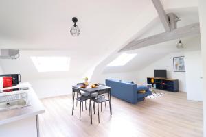 a living room with a table and a blue couch at Le Travi - Studio Hyper-Centre in Bergerac