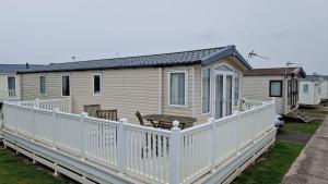 a mobile home with a white fence at Camber Sands Holiday Park in Camber