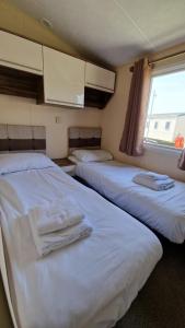 two beds in a small room with a window at Camber Sands Holiday Park in Camber