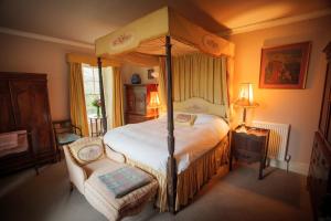 um quarto com uma cama de dossel e uma cadeira em Gelly Dylan Thomas Paradise em Lampeter