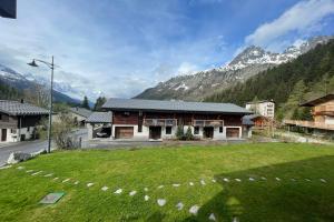 un bâtiment avec une cour en herbe en face d'une montagne dans l'établissement Sunny Nest - View Of MB Montroc - Happy Rentals, à Chamonix-Mont-Blanc