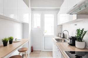 Biała kuchnia z białymi szafkami i zlewem w obiekcie Comfy 1BR Apartment in Ampelokipoi by UPSTREET w Atenach