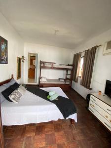 ein Schlafzimmer mit einem großen Bett und einem TV in der Unterkunft Casa de Praia Suítes in Saquarema