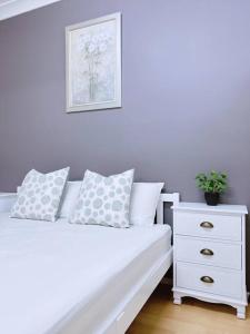 een wit bed met 2 kussens en een dressoir bij Two beds Premier Guest Suite in Castle Hill