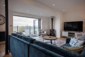 sala de estar con un gran sofá azul y TV en Stylish beachside house with superb coastal views, en Westward Ho