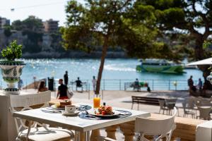 a table with food and drinks on a balcony with the beach at THB Felip - Adults Only in Porto Cristo