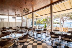 un restaurante con mesas, sillas y ventanas en THB Felip - Adults Only en Porto Cristo