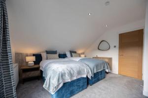 Un dormitorio con una cama grande y una mesa con lámparas. en Stylish beachside house with superb coastal views, en Westward Ho