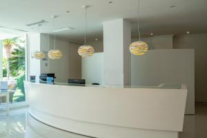 a lobby with a reception desk and pendant lights at THB Sa Coma Platja in Sa Coma