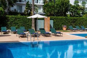 a swimming pool with chairs and an umbrella next to a swimming pool at THB Niagara in Playa de Palma