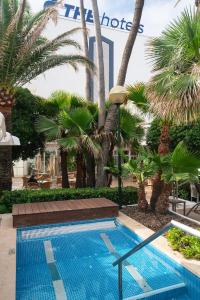 una piscina en un complejo con palmeras en THB Gran Playa - Adults Only, en Can Picafort