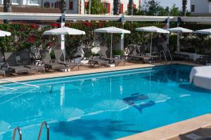 - une piscine avec des chaises longues et des parasols dans l'établissement THB Gran Playa - Adults Only, à Can Picafort