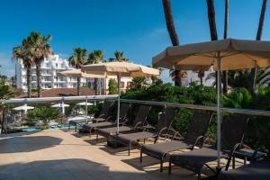 a row of chairs and umbrellas next to a pool at THB Gran Playa - Adults Only in Can Picafort