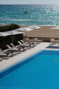 uma piscina com cadeiras e guarda-sóis junto à praia em THB El Cid - Adults Only em Can Pastilla