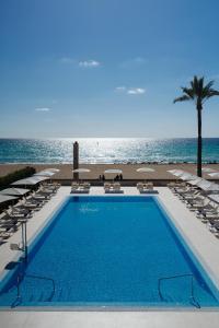 a swimming pool with chairs and the ocean in the background at THB El Cid - Adults Only in Can Pastilla