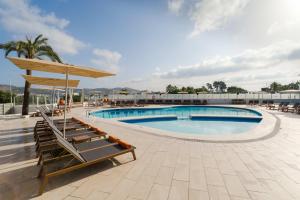 una piscina en un hotel con sillas y sombrilla en THB Ocean Beach, en Bahía de San Antonio