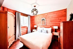 a bedroom with a white bed and wooden walls at Cordelia with SPA Lake Nominingue 1min in Nominingue