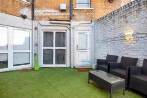 een patio met 2 stoelen, een tafel en een bakstenen muur bij 5WJB - Spacious 1 Bed Flat in London in Londen