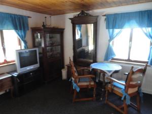 a living room with a tv and a table and chairs at Chata SLUKA in Poniklá