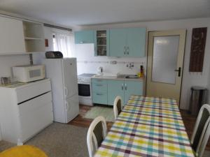 a kitchen with a table and a white refrigerator at Chata SLUKA in Poniklá