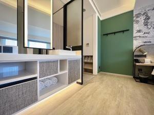 a bathroom with a white counter and green walls at Boutech JianTan Hotel in Taipei