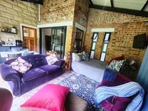 a living room with a purple couch and a brick wall at Naauwpoort View in Clarens
