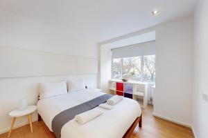 a white bedroom with a large bed and a window at Modern 2 Bed Apartment near Acton Central Tube Station - Sleeps 4 in London