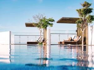 头顿ibis Styles Vung Tau的一群人躺在游泳池旁的躺椅上