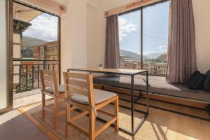 a table and two chairs in a room with a balcony at Hotel Dralha in Thimphu