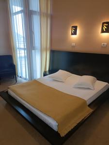 a large bed in a bedroom with two lights at Hotel Maxim in Arad