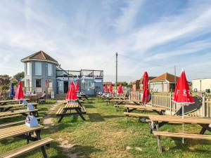 a row of picnic tables with red umbrellas on them at The Waves B&B in Birchington