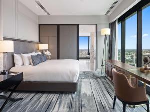 a bedroom with a large bed and a desk and chairs at Sofitel Adelaide in Adelaide