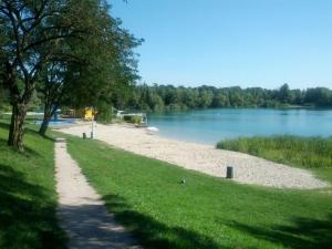 a sandy path next to a river with a tree at Apartment Muggensturm am Badesee in Muggensturm