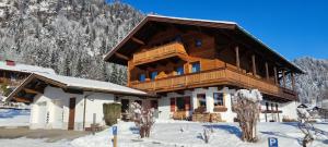 a log cabin in the snow with snow covered mountains at Ferienwohnungen Marietta in Reit im Winkl