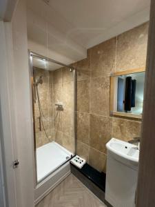 a bathroom with a shower and a tub and a sink at The Waves B&B in Birchington