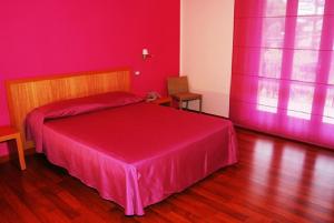 um quarto vermelho com uma cama com uma colcha rosa em Hotel I Colori em SantʼAntìoco
