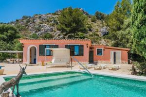 a house with a giraffe standing next to a swimming pool at AGUAIT II - VILLA WITH PRIVATE MOUNTAIN PATH-BEACH APPROX 5 MIN WALKING BEACH,property belong Puerto Pollensa Villas and apartments in Pollença