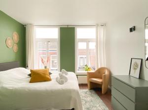 1 dormitorio con paredes verdes y 1 cama con silla en Charming house in city centre Oud-Beijerland, en Oud-Beijerland